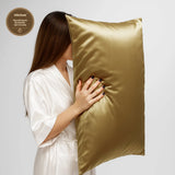 Woman holding a gold silk pillow with shiny hair on white background