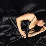Black silk pillowcase from SilkSleek on a bed with a woman peacefully sleeping