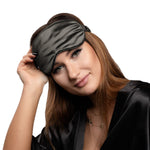 Woman wearing a charcoal silk eye mask on a white background