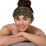 Woman wearing a green plaid sleep mask against a neutral background
