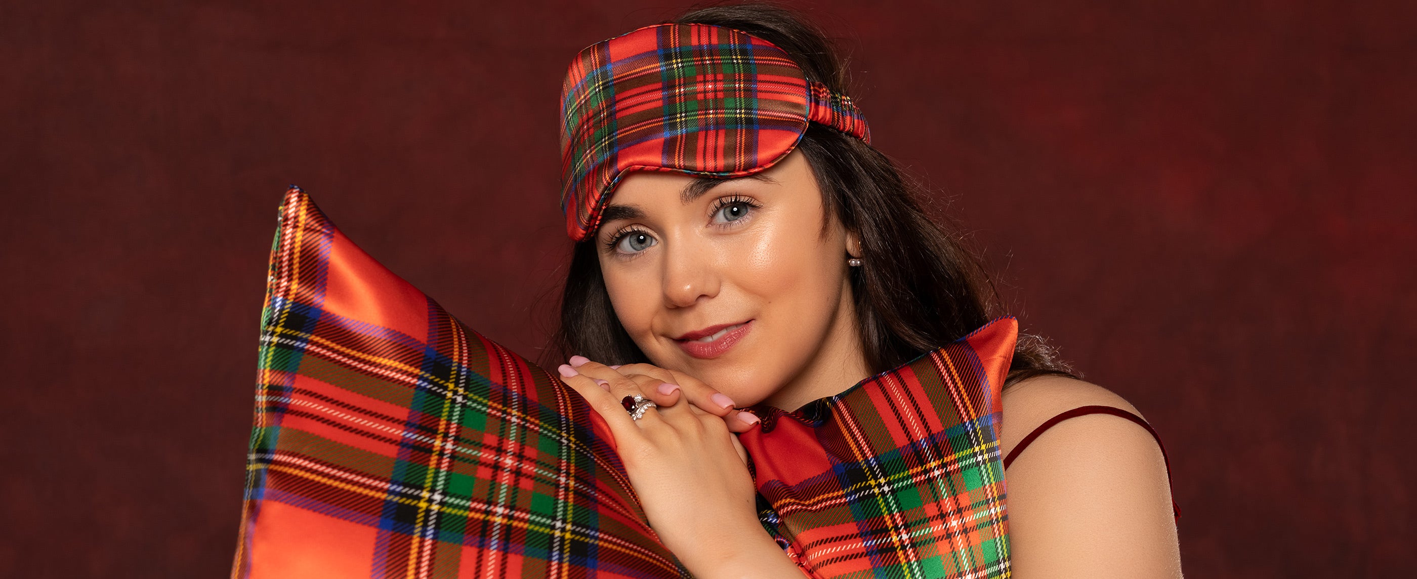 Woman wearing a red silk plaid eye mask and matching tartan silk pillow