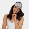 Woman wearing a leopard print sleep eye mask on a white background