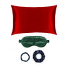 Red silk pillowcase, green sleep mask, and two navy scrunchies on a white background
