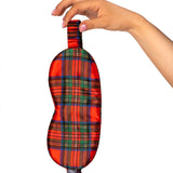 Hand holding a red plaid eye mask against a white background