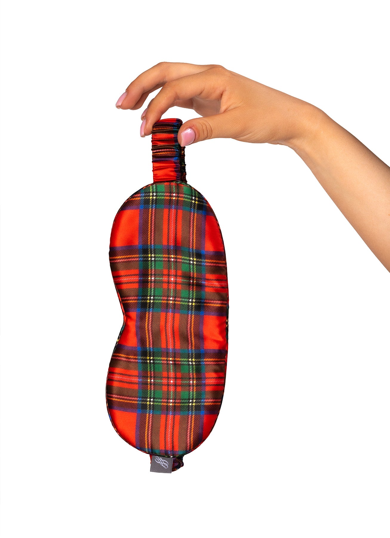 Hand holding a red plaid eye mask against a white background