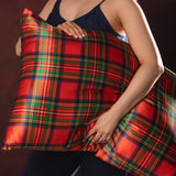 Person holding a  red and green plaid silk pillow